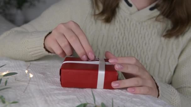 4k żeńskie ręce wziąć gałąź eukaliptusa, aby zapakować prezent z czerwonego papieru kraft na Boże Narodzenie lub Walentynki na łóżku wieczorem, ferie zimowe i sezon sprzedaży, zbliżenie - Materiał filmowy, wideo
