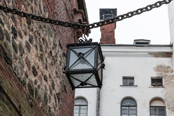 VYBORG, RUSSIA - OCTOBER 31, 2021: Old style lamp in Vyborg Castle. Vintage lamp hanging on a metal chain - Foto, imagen