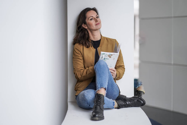 attractive brown hair student woman journaling thoughtful with pen in casual outfit in a modern university lobby on a white background - Φωτογραφία, εικόνα