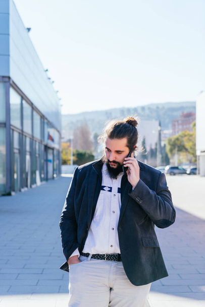 Jeune homme d'affaires parlant mobile à côté des bureaux - Photo, image