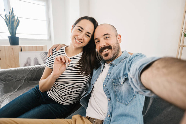 Joyeux jeune couple adulte prenant selfie photo après avoir déménagé dans un nouvel appartement - Photo, image