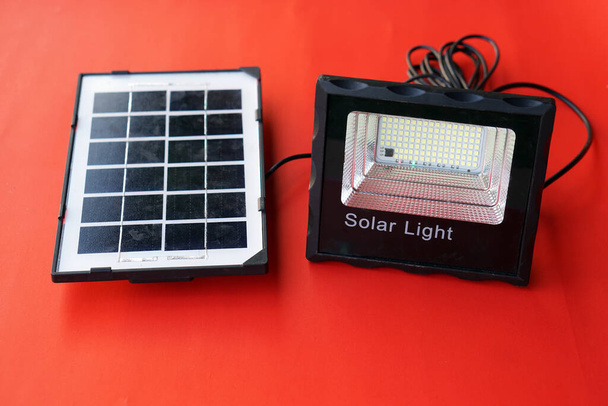 Mini solární panel a sluneční světlo sady na červeném pozadí. Koncepce s využitím zelené a čisté energie pro životní prostředí. Obnovitelná energie, Přírodní energie ze slunečního svitu ke snížení globálního oteplování.   - Fotografie, Obrázek