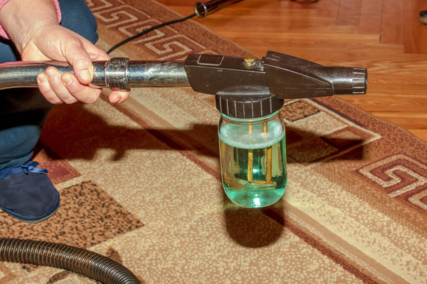 Le processus de nettoyage du tapis avec un aspirateur avec un filtre à eau. Buse pour l'aspirateur pour la formation de mousse de nettoyage. - Photo, image