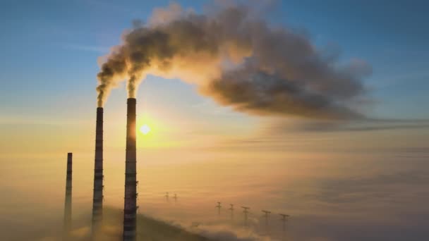 Воздушный вид на высокие трубы угольной электростанции с черным дымом, движущимся вверх загрязняющей атмосферу на восходе солнца - Кадры, видео