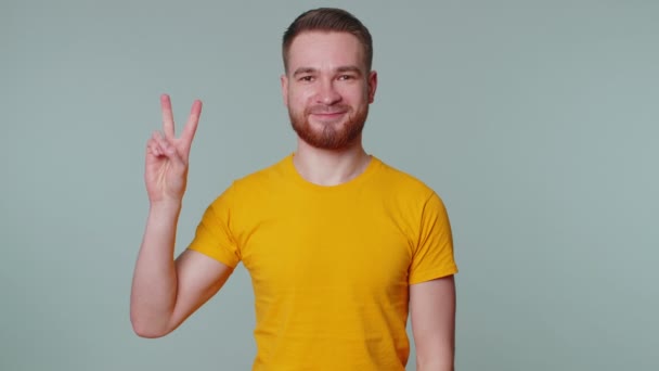 Schöner, stilvoll lächelnder Mann zeigt Siegeszeichen, hofft auf Erfolg und Sieg, macht Friedensgeste - Filmmaterial, Video