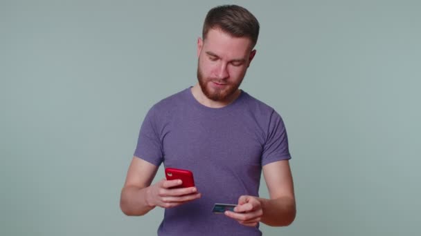 Hombre usando tarjetas de crédito y teléfono inteligente durante la transferencia de dinero, compras en línea - Metraje, vídeo