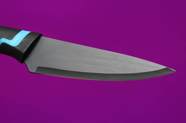 grand couteau de cuisine noir sur fond violet - Photo, image