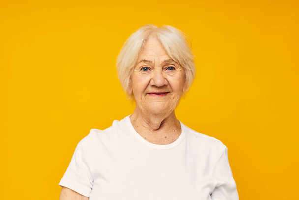 Photo of retired old lady in white t-shirt posing fun yellow background - Foto, Bild