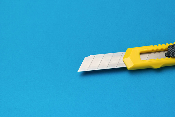 Een opgevouwen briefpapier mes op een helderblauwe achtergrond. Minimalistisch concept. - Foto, afbeelding