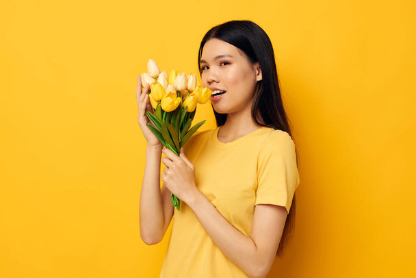 Frau mit asiatischem Aussehen mit einem Strauß gelber Blumen Romantik-Studio-Modell unverändert - Foto, Bild