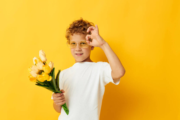 cute boy with a bouquet of yellow flowers isolated background unaltered - Фото, изображение