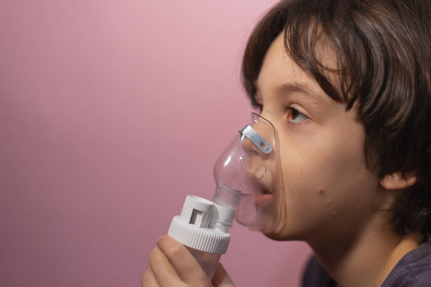 το παιδί εισπνέει, το αγόρι εισπνέει το φάρμακο μέσω της μάσκας, μάσκα νεφελοποίησης, θεραπεία της νόσου - Φωτογραφία, εικόνα