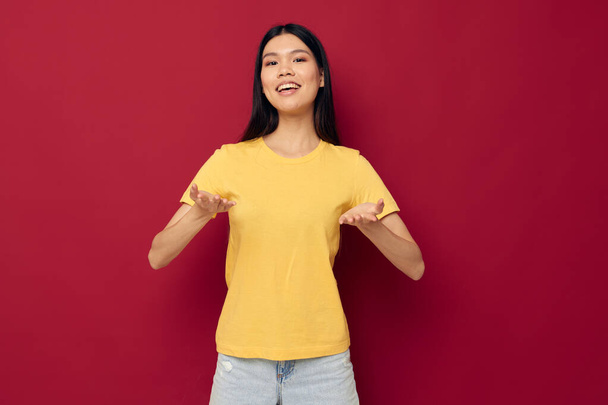 Portrait Asian beautiful young woman yellow casual t shirt smile posing red background unaltered - Fotografie, Obrázek