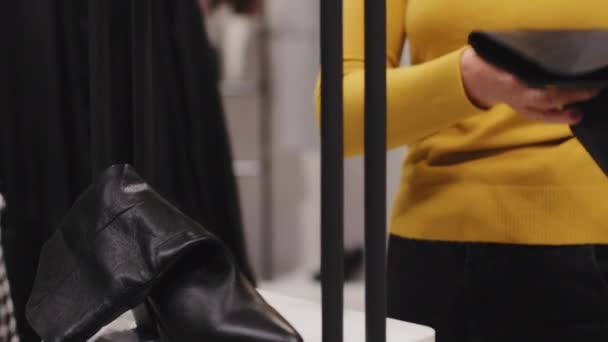 Lähikuva valkoihoinen tyylikäs keski-ikäinen nainen asiakas shopper muodikas putiikki vaatekauppa valitsee kengät omistaa naisten musta boot huolellisesti tarkastellaan laatua tuotteen osto alennus myynti - Materiaali, video