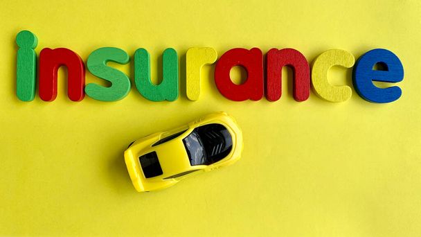 黄色の背景を持つ保険やモデル車のテキストのトップビュー。概念 - 写真・画像