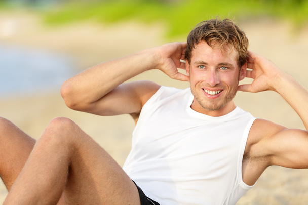 Man doing crunches sit-ups on beach - Photo, Image