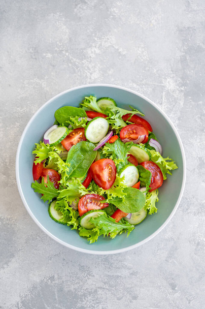 Salade de légumes frais et fromage dans un bol sur fond de béton. Salade grecque, plat végétarien. Vue du dessus - Photo, image