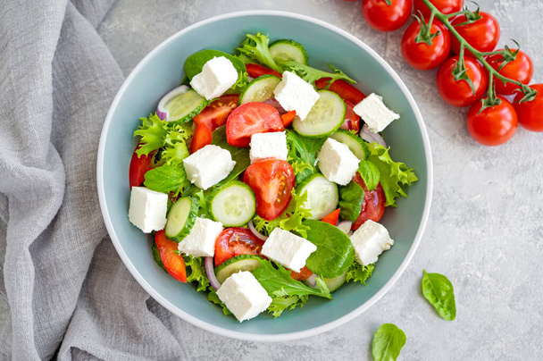 Taze sebzeli salata ve çimento kaplı bir kasede peynir. Yunan salatası, vejetaryen yemeği. Üst görünüm - Fotoğraf, Görsel