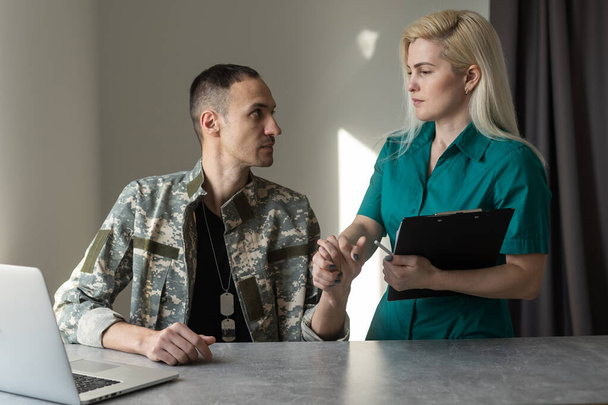 Female doctor and worried military officer discussing about problems he has during psychotherapy treatment. - Фото, изображение