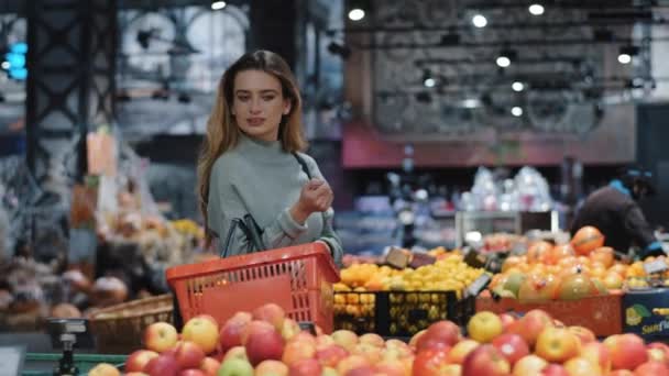 Кавказка потребительница покупатель женщина покупатель с корзиной прогулки в продуктовый магазин супермаркет ищет товары, глядя на киоски со свежими вкусными тропическими фруктами, покупая еду делает выбор скидки - Кадры, видео