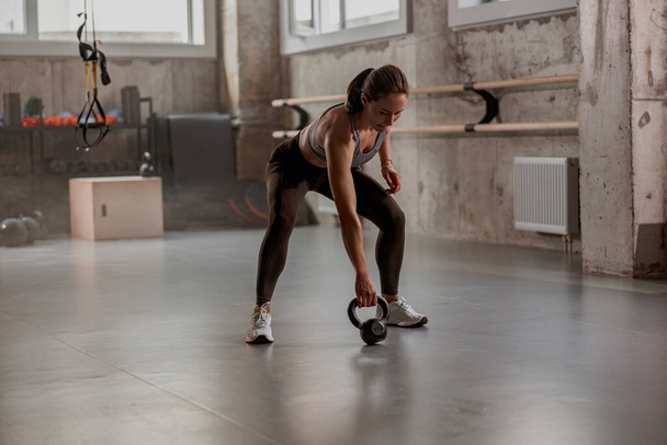 Вмістити жінку робити тренування з гантелі в спортзалі
 - Фото, зображення