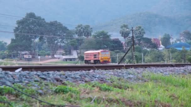 Locomotive diesel corrono su binari per fermarsi alla stazione ferroviaria di Lamphun. Questa ripresa è stata girata al Tha Chomphu White Bridge durante il tramonto. - Filmati, video