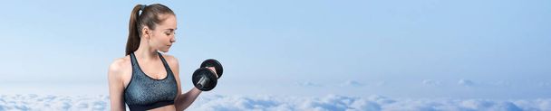 Uma jovem atlética magro em sportswear executa um conjunto de exercícios. Fitness e estilo de vida saudável contra o fundo do céu nuvens. - Foto, Imagem
