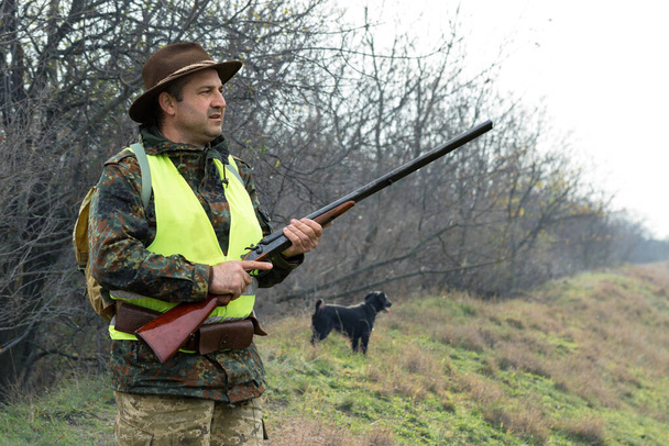 Hombre cazador en camuflaje con un arma durante la caza en busca de aves silvestres o de caza. Temporada de caza de otoño
. - Foto, Imagen