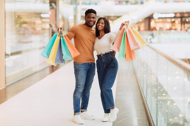Hermosa pareja negra sosteniendo bolsas de compras mirando posando en la cámara - Foto, Imagen