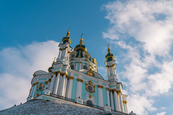 kerk van St. Andreas rijst op tegen de achtergrond van de blauwe lucht met witte wolken. Kijk omhoog. Kiev, Oekraïne. 02 2022 - Foto, afbeelding