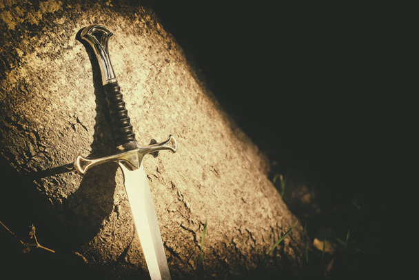 mysterious and magical photo of silver sword in the England woods. Medieval period concept - Photo, image