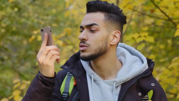 Mladý muž stojící venku zaostával za turistickou skupinou ztracen ve dřevě cestování s batohem zvedání mobilních hovorů žádné spojení frustrovaný při pohledu na obrazovce smartphone obavy z problému s internetem - Záběry, video