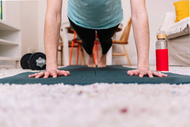 Close-up van de handen van een vrouw op een mat terwijl ze een plank doet. Fitness concept. - Foto, afbeelding
