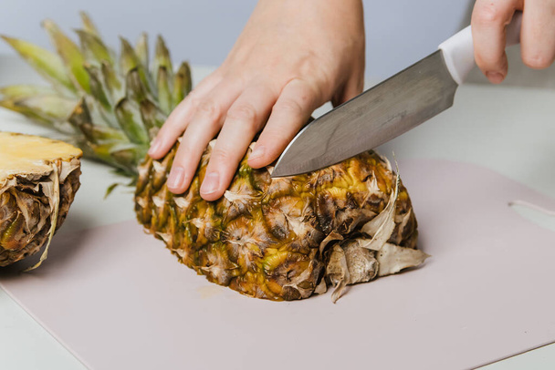 As mãos femininas cortam o abacaxi suculento. Fruta de dieta deliciosa - Foto, Imagem