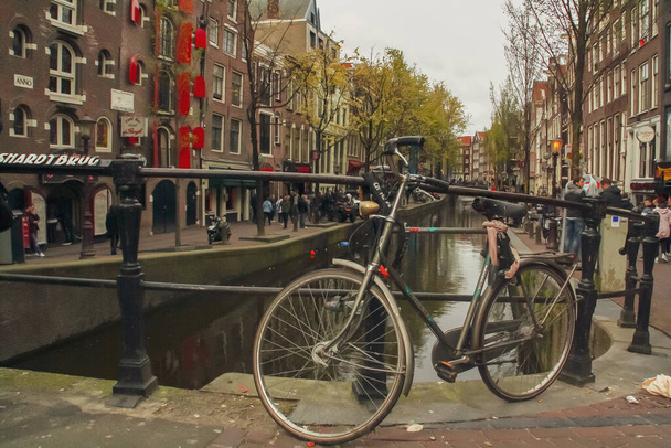 Amsterdam, Holandia; 04 30 2016. Zaparkowałem rowery na poręczy mostu nad kanałem. Jest to tradycyjny i popularny transport w Holandii. - Zdjęcie, obraz