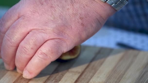 Человек режет ломтики инжира на открытом воздухе - Кадры, видео