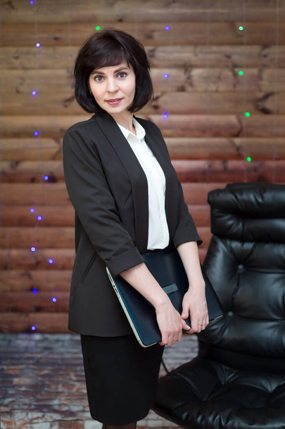 A business lady in a formal suit with a laptop in her hand on a festively decorated wooden background. - Фото, изображение