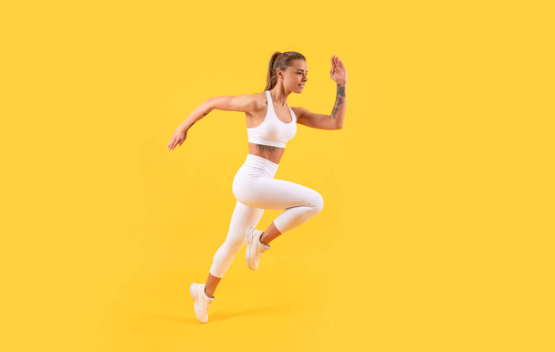 黄色い背景でスポーツウェアを着たフィットネスガールランナー - 写真・画像