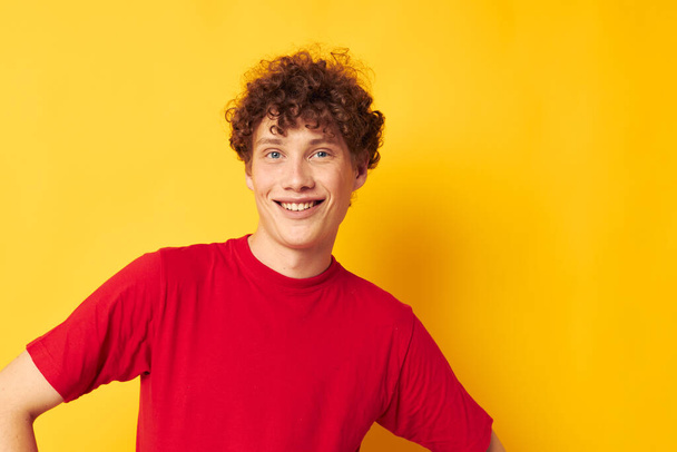 portrait of a young curly man red t shirt fun posing casual wear isolated background unaltered - Foto, afbeelding