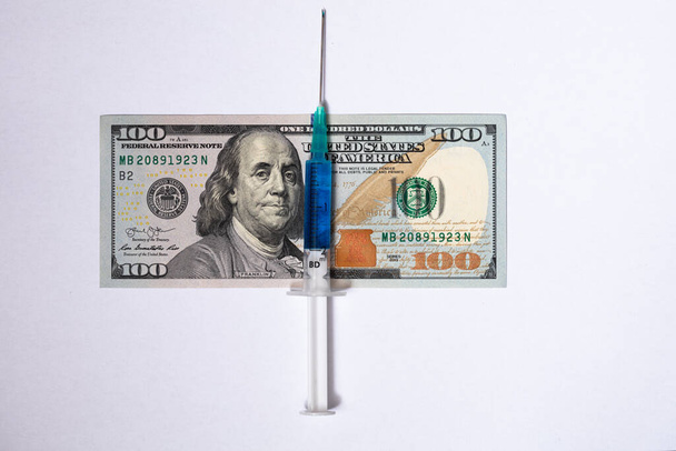 Jeringa sobre fondo de billetes de 100 dólares - Foto, Imagen