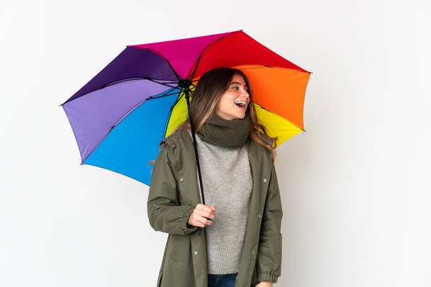 Young caucasian woman holding an umbrella isolated on white background laughing in lateral position - Φωτογραφία, εικόνα