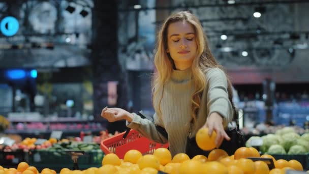 Кавказька жінка споживає покупець жіночої статі з кошиком для покупок в продуктовому магазині в супермаркеті вибирає апельсиновий соковитий цитрус смачний фрукт купляє харчові знижки - Кадри, відео