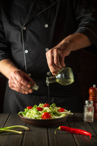 Lo chef versa l'olio d'oliva in una ciotola di insalata. Cucinare cibo saporito e sano con serie di vitamine. - Foto, immagini