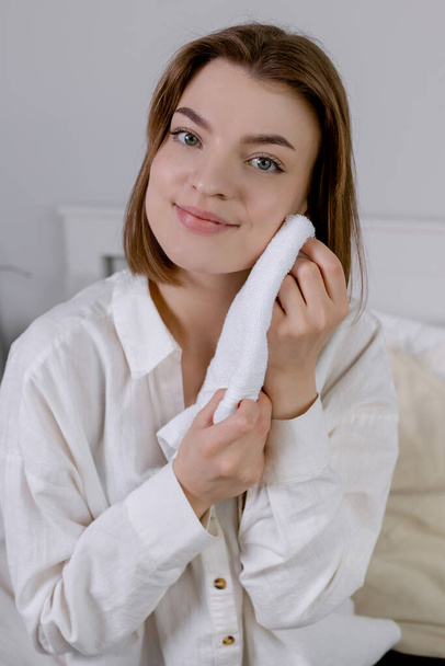 Young woman smiling and holding a towel near her face Clean skin without makeup - 写真・画像