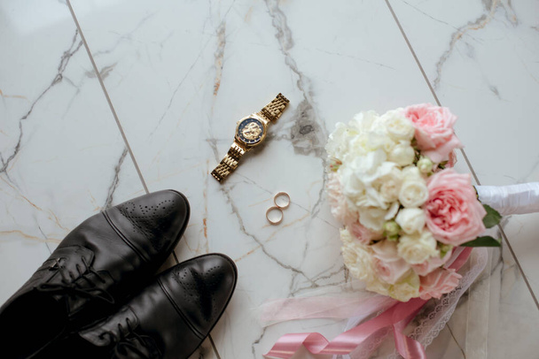 Bir buket beyaz ve pembe gül, alyans, erkek saati ve damat ayakkabısı. düğün detayları  - Fotoğraf, Görsel