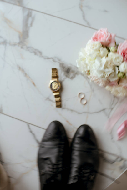 A bridal bouquet of white and pink roses, wedding rings, men's watches and the groom's shoes. wedding details  - Fotó, kép