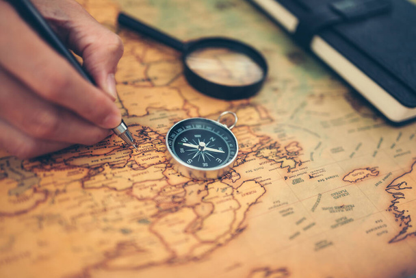 Hand use pen and marking and Magnetic compass, magnifying glass and diary on world map. Travel , Adventure and Discovery concept. - Fotografie, Obrázek