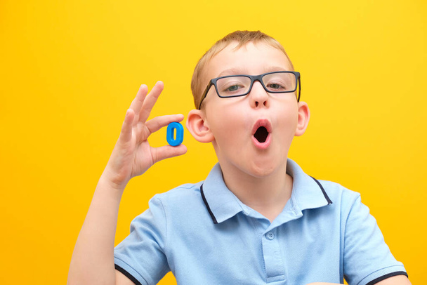 speech therapy. on a yellow background, a boy with glasses learns to pronounce sounds and words correctly - Foto, afbeelding