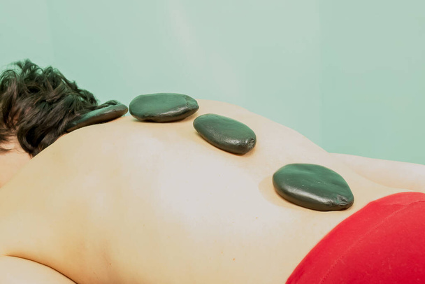 Stenen therapie - hete stenen massage voor ontspanning. Verhoogt de spierspanning. Getooid - Foto, afbeelding
