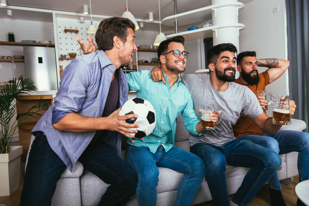 Spannende vrienden die voetbal kijken en bier en popcorn vasthouden - Foto, afbeelding